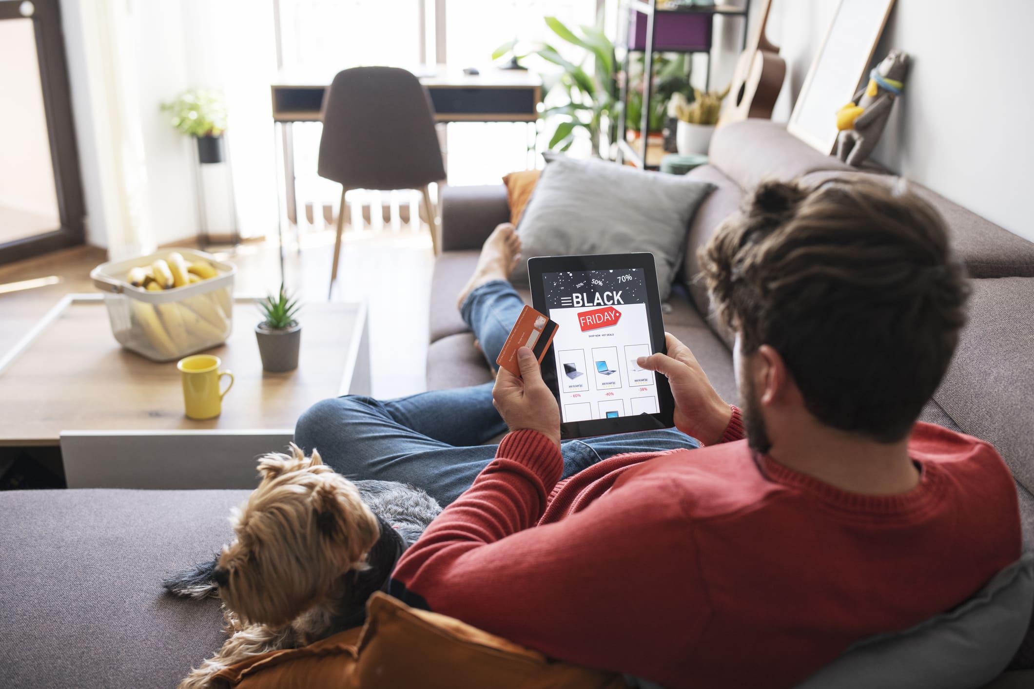 Man and her dog is relaxing at home and shopping electronics online during Black Friday sale.